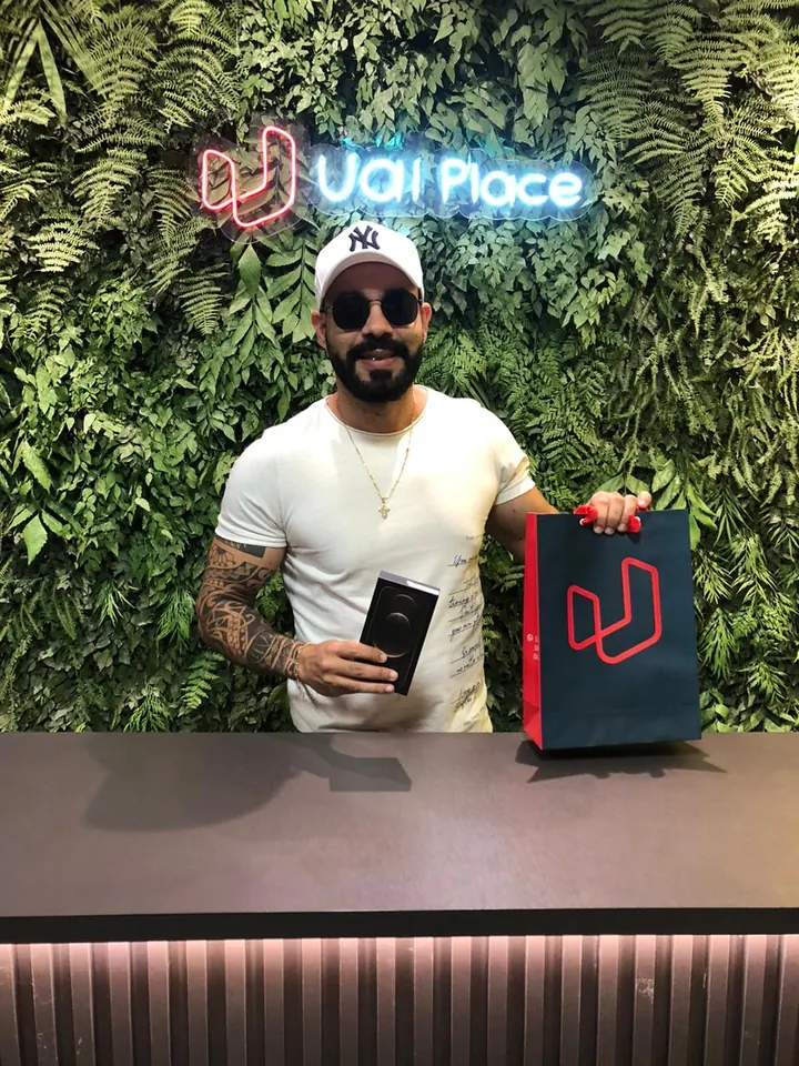 Cliente da UaiPlace com o aparelho novo e a sacola da loja