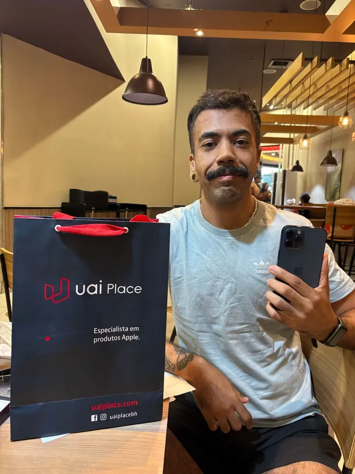 Cliente da UaiPlace com o aparelho novo e a sacola da loja